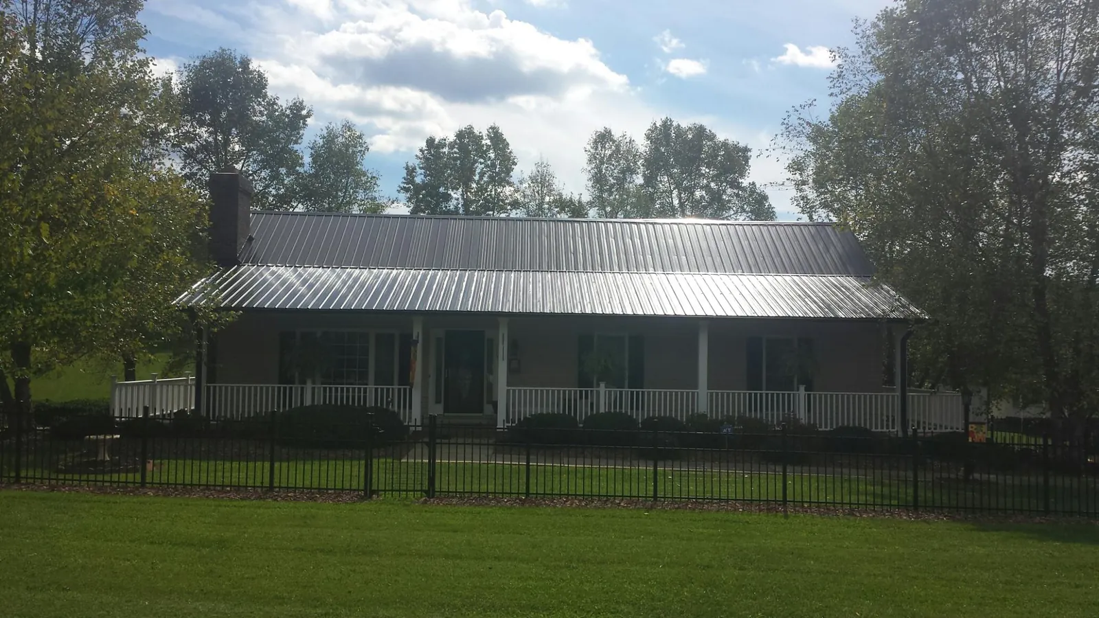 Gray metal roof on a brick ranch with a full width front porch — Gutter Guard Installation work by our crew in Cocoa