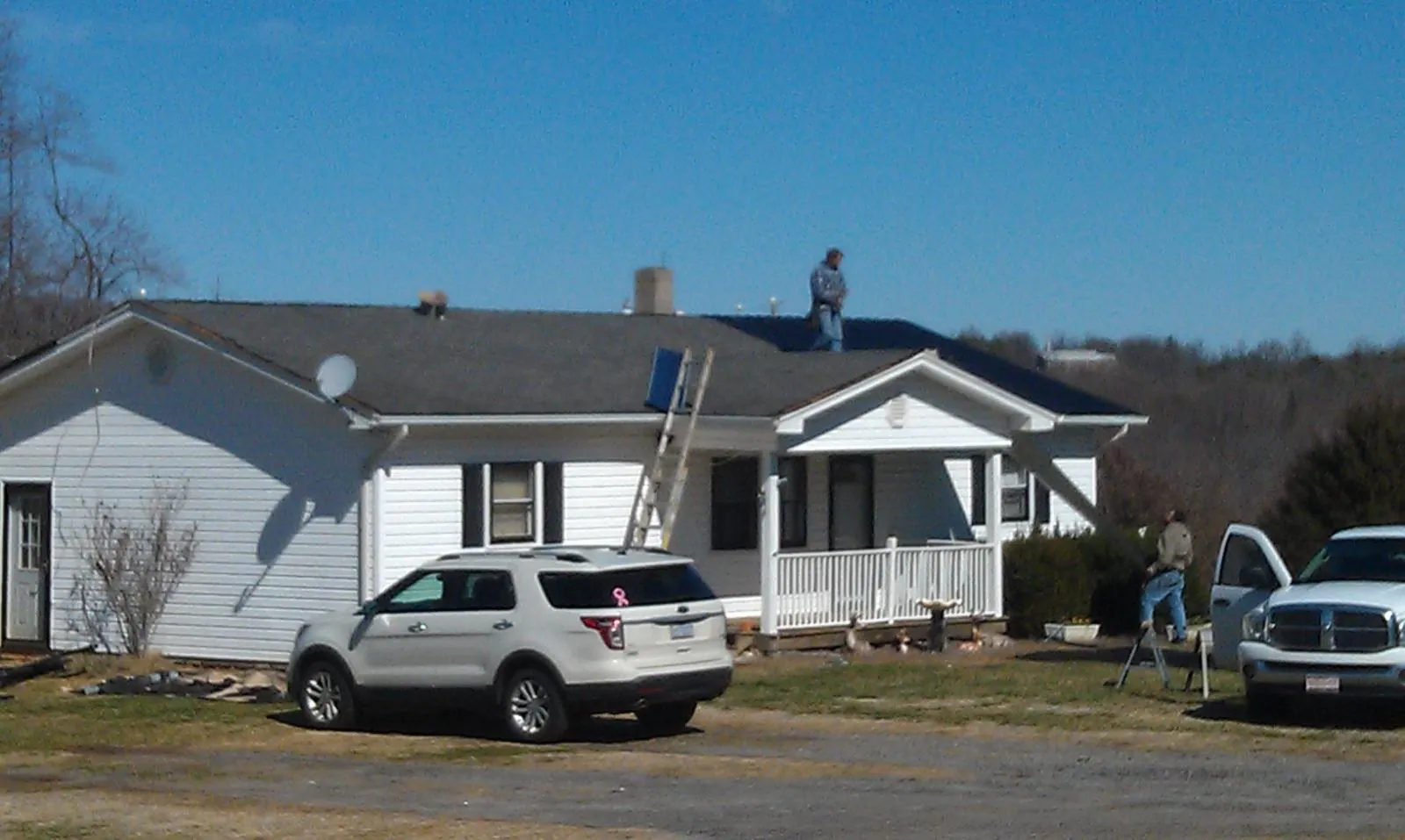Roofers stripping shingles from a white ranch house roof in Cocoa