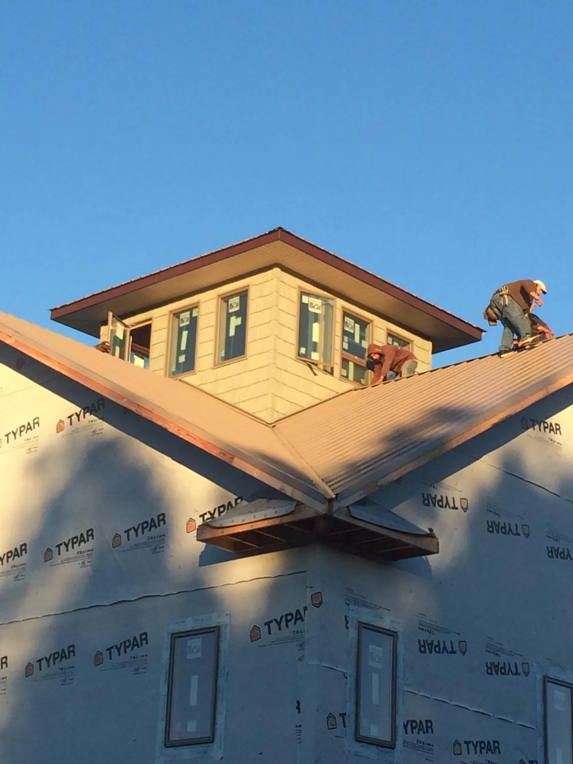 Roofers working around a rooftop cupola on a new metal roof at sunset — Roof Waterproofing in Cocoa by Roofing Brothers